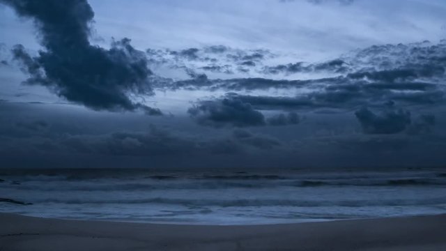 Dark clouds over ocean time lapse. Day to night transition on beach.