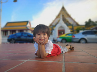 The boy laying down relaxable in public place.