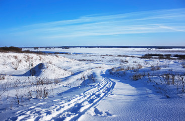 Country road covered with snow in the winter field