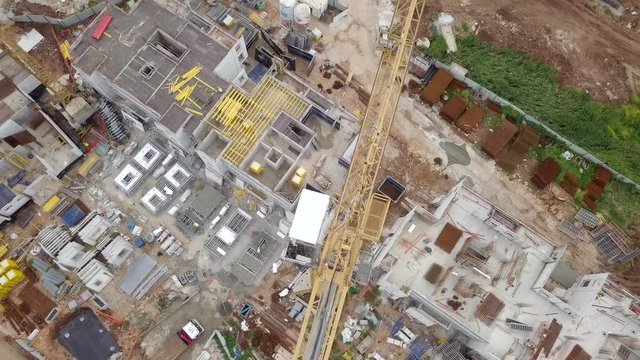 Construction site - Aerial footage of a large Residential compound during early stages of construction, with cranes and green surrounding environment.
