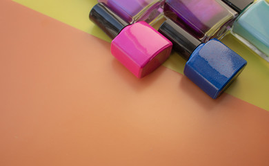 Bottles of nail polish. A group of bright nail polishes on a colored, yellow background. With empty space on the left.