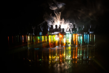 Vape concept. Smoke clouds and vape liquid bottles on dark background. Light effects. Useful as...