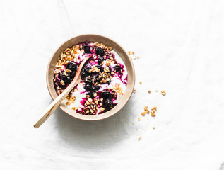 Greek yogurt with granola and blueberry sauce on light background top view