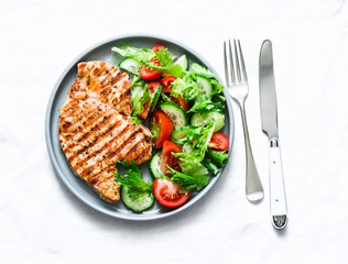 Grilled turkey chops and vegetables salad on a light background, top view. Healthy food diet concept