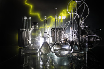 Pharmacy and chemistry theme. Test glass flask with solution in research laboratory. Science and medical background. Laboratory test tubes on dark toned background
