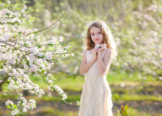 Fototapeta na wymiar Gorgeous blonde girl standing near blossom tree and smiling. Girl near tree. Blonde girl outdoor smiling. Girl in garden. Young female in blossoming orchard. Spring concept. 