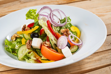Greek salad with feta cheese on the wooden background