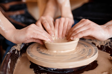 happy family on a creative joint vacation. romantic couple in love working together on potter wheel and sculpting clay pot