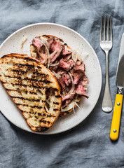 Beef steak ciabatta grilled sandwiches with homemade mayonnaise mustard sauce on a grey background, top view. Copy space