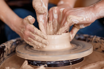 happy family on a creative joint vacation. romantic couple in love working together on potter wheel and sculpting clay pot