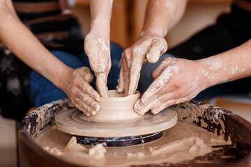 happy family on a creative joint vacation. romantic couple in love working together on potter wheel and sculpting clay pot