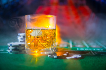 gambling, fortune, game and entertainment concept - close up of casino chips and whisky glass on table