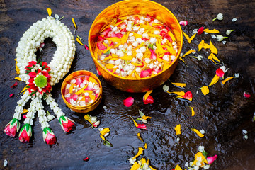Songkran Festival summer of Thailand on Banana leaf background, Songkran festival Thailand theme Songkran water bowls decorated with jasmine, rose and marigold petals over green on wood Background
