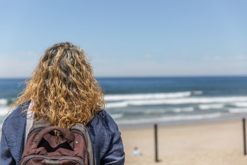A tourist woman, placidly observes a beach on a sunny day