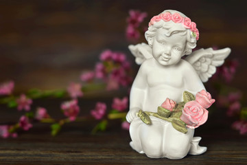 Guardian angel and spring flowers on wooden background