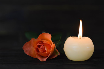 Obraz na płótnie Canvas Burning candle and rose on dark background