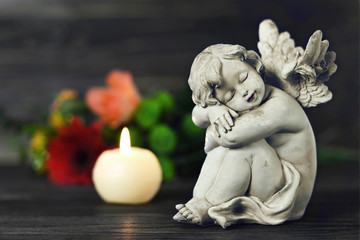 Funeral candle, guardian angel, and flowers