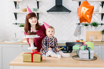 young beautiful mother and her little daughter are celebrating a birthday. cake with candles. happy birthday baby