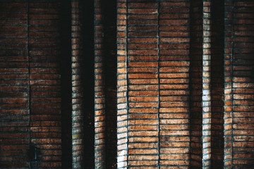 A dark atmospheric wall of oblong bricks near the house entrance with several triangle displacements; the dark texture of a brick wall inside of a porch of a residential house in Barcelona