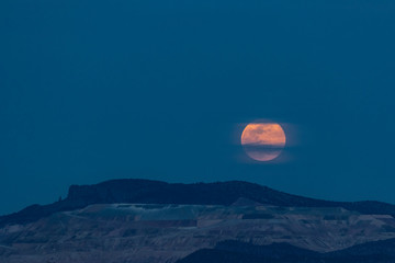 A super moon rises over a mountain in the desert