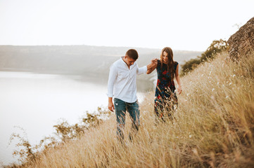 Beautiful couple walking on the hill with lake on background, a romantic day together