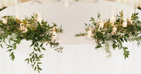 Wedding table, with candles in glass and green leaves, element of decoraton