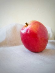 An ugly red organic Apple on a light linen napkin.