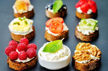 Ricotta and crostini appetizers with fillings on a black background