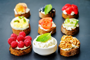 Ricotta and crostini appetizers with fillings on a black background