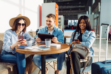 Three tourists with phones waiting in airport
