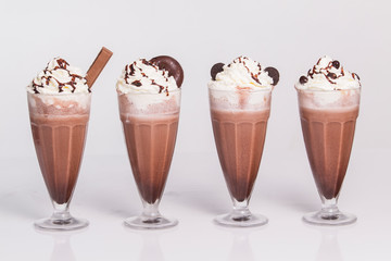 Hot chocolate with whipped cream in mugs isolated on white