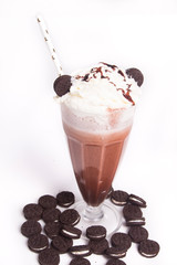 Chocolate milkshake with chunks of chocolate and cookies on top, isolated on white
