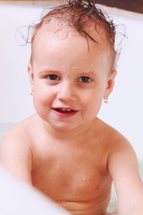Beautiful little girl bathing in the water in the bath