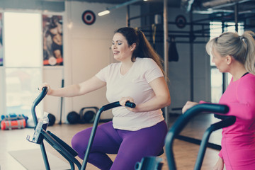 Fat woman sits tired on stationary bike