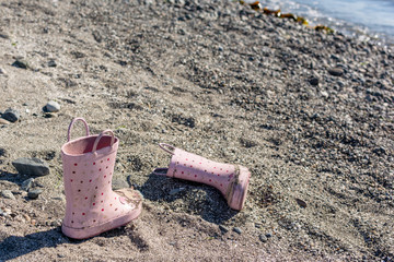 Abandoned pink boots on the beach