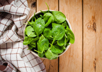 Baby spinach in a bowl on wooden table, top view