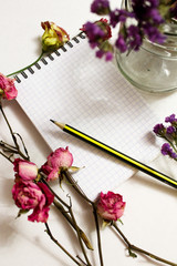Fototapeta na wymiar Kraft paper spiral notebook, white pen and summer flowers on rustic wooden background. Mock-up