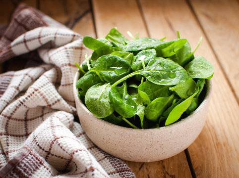 Close-up of baby spinach in a bowl on wooden table