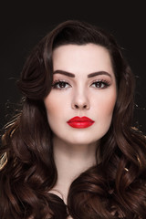 Portrait of young beautiful brunette with curly hair and red lipstick