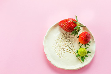 Fresh strawberries on white plate on pink background. Children breakfast, food concept