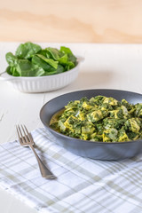 Bowl of spinach paneer with dish of fresh spinach