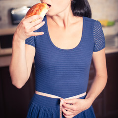 young woman holds pie and a measuring tape