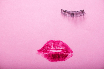 Creative woman face made of eyelashes, wig eyebrows and red lipstick stains as lips.