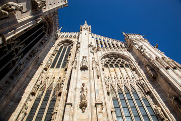 details of the statues, windows and stained glass windows of the Duomo of Milan on a sunny day