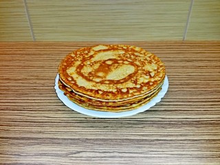 Pancakes on white porcelain plate, with spiral drawing, tiles in the background
