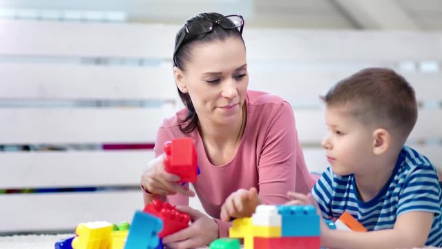 Medium close-up happy adorable mother enjoying playing game toys cubes with little cute son
