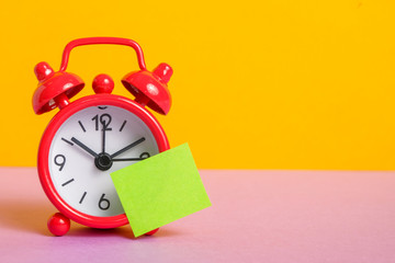 Red retro clock on yellow background. Green sticker for text.