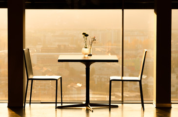 a table and two chairs in front of a glass in sunset