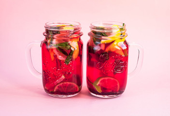 Two jars of tasty cold lemonade on a pink background. View from above