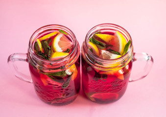 Two jars of tasty cold lemonade on a pink background. View from above